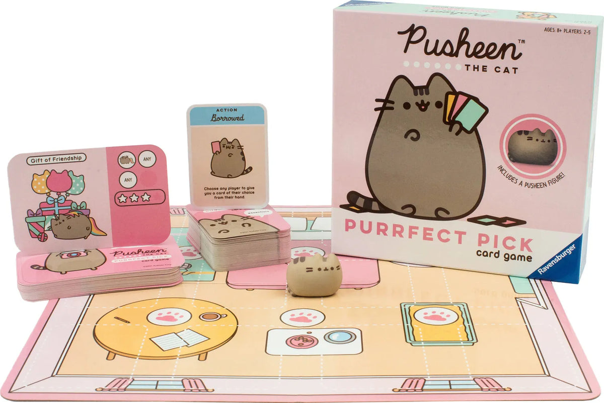 Pusheen kāršu spēle ar rozā spēles laukumu, ilustrētām kārtīm un mazu Pusheen figūriņu uz galda.