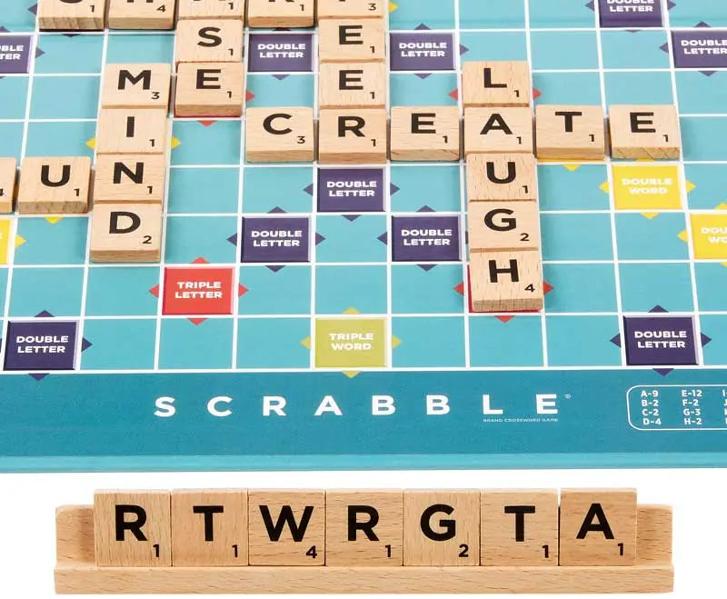 Scrabble spēles laukums ar koka burtiem uz statīva un krāsainiem lauciņiem vārdu veidošanai.