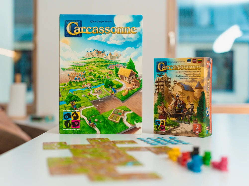 Carcassonne pamatspēle un paplašinājums Tirgoņi un būvnieki ar krāsainiem spēles lauciņiem un koka figūriņām uz galda.