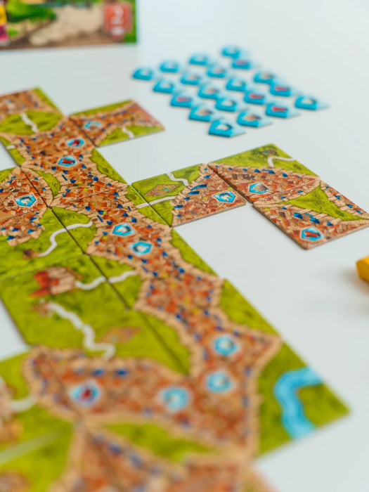 Carcassonne paplašinājuma Tirgoņi un būvnieki kartona lauciņi ar pilsētu, ceļu un preču simboliem uz balta fona.