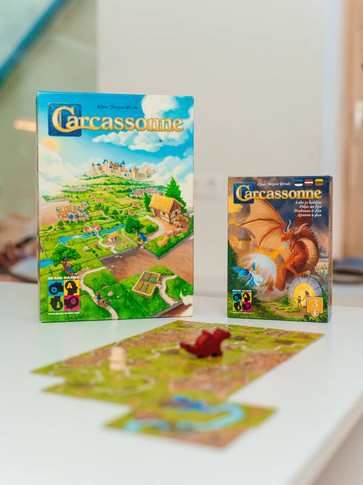 Carcassonne pamatspēle un paplašinājums Pūķis un feja ar krāsainām spēles kārtīm un pūķa figūriņu uz galda.