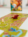 Carcassonne paplašinājuma spēles laukums ar sarkanu koka pūķa figūriņu un spēles kasti fonā.