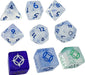 Cosmere RPG Stormlight kauliņu komplekts ar caurspīdīgiem, ziliem un zaļiem elementiem un unikāliem simboliem.