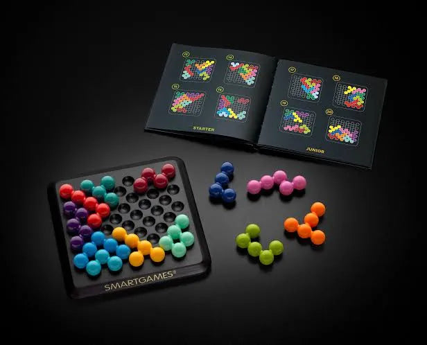 SmartGames IQ Deluxe loģikas spēle ar krāsainām 3D detaļām, spēles pamatni un uzdevumu grāmatiņu uz melna fona.