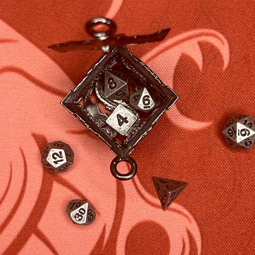 Sudraba krāsas metāla D6 kauliņa formas atslēgu piekariņš ar septiņiem 5 mm miniatūriem galda spēļu kauliņiem.