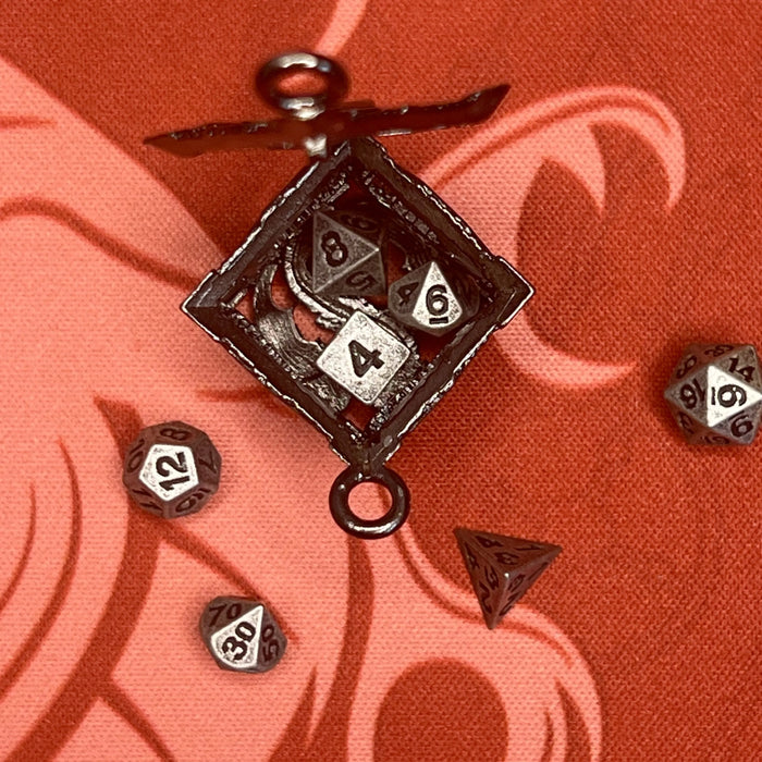 Sudraba krāsas metāla D6 kauliņa formas atslēgu piekariņš ar septiņiem 5 mm miniatūriem galda spēļu kauliņiem.