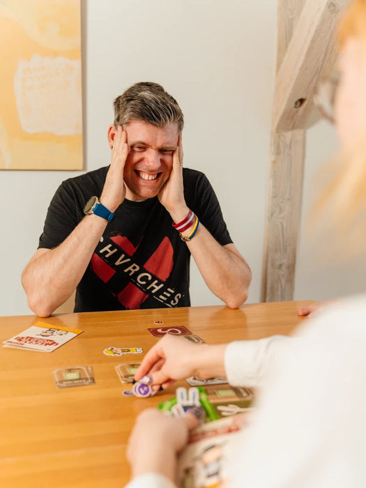 Cilvēki spēlē kāršu spēli Texas Hold It uz koka galda ar krāsainām spēļu kārtīm un žetoniem.