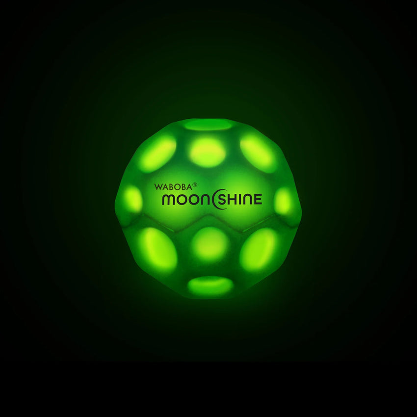 Zaļa, tumsā spīdoša 6,35 cm Waboba MoonShine bumbiņa ar krāteriem un melnu logotipu uz tumša fona.