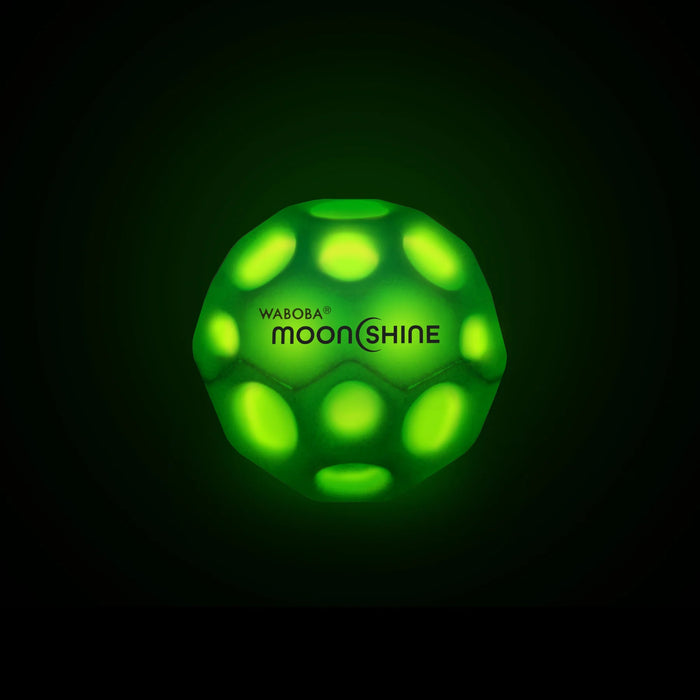 Zaļa, tumsā spīdoša 6,35 cm Waboba MoonShine bumbiņa ar krāteriem un melnu logotipu uz tumša fona.